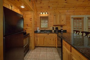 A kitchen with wooden cabinets, a refrigerator, a sink, and a coffee maker. - New Listing! 2 Minutes from Pigeon Forge Parkway! Hot tub/Pool table/Romantic! (Pigeon Forge)