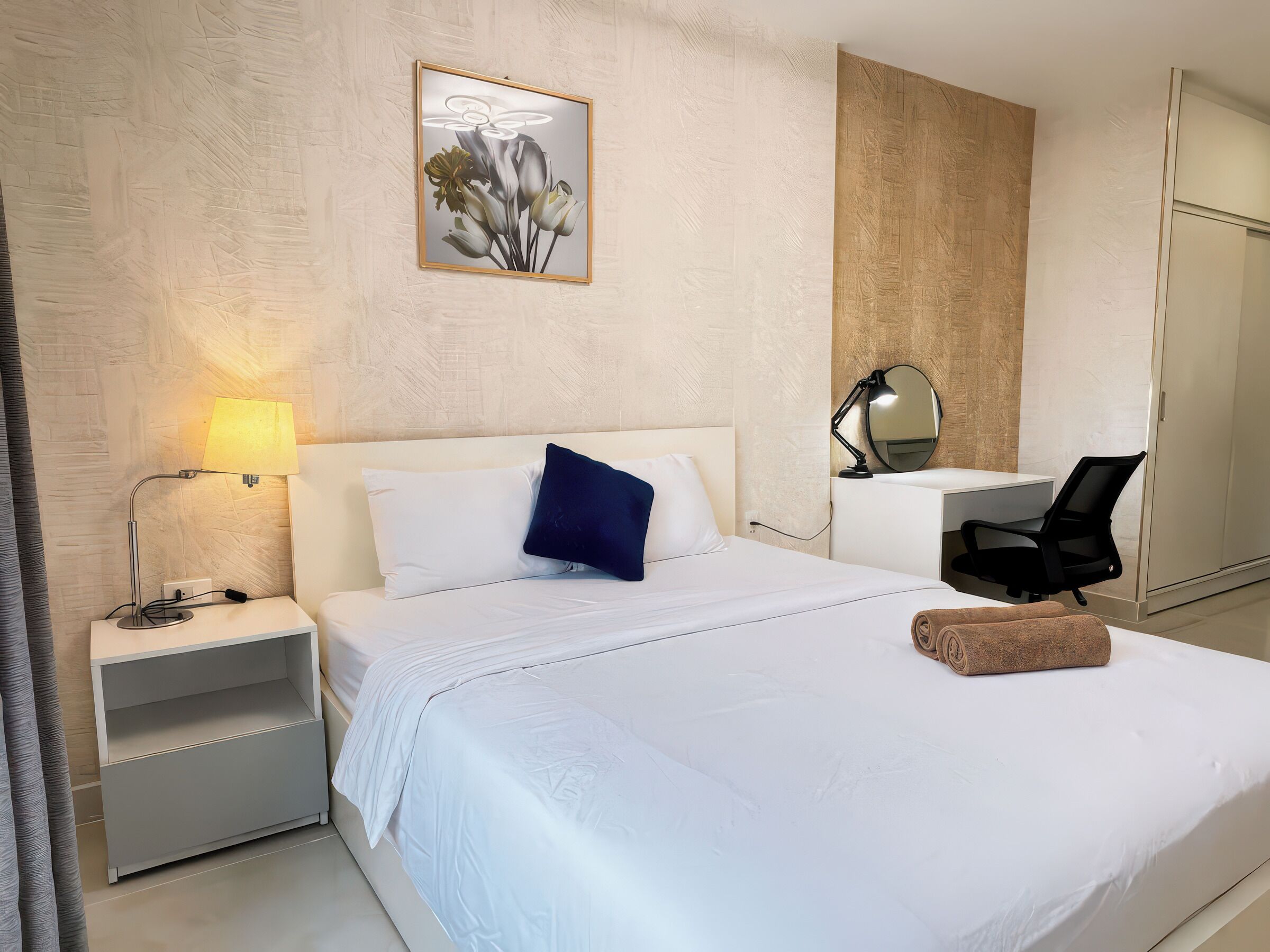 Ein Hotelzimmer mit einem Bett, einem Schreibtisch, einem Sessel, einer Lampe und einem Bild an der Wand.