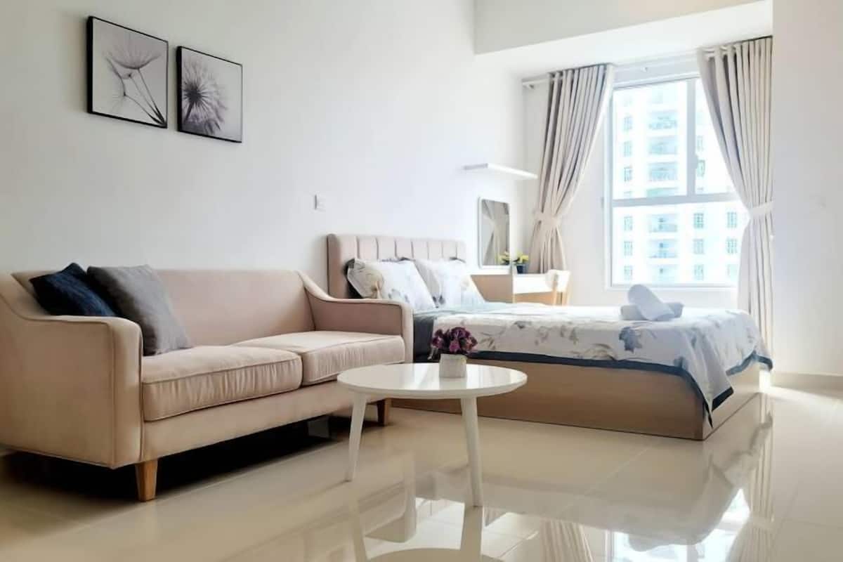 Una habitación de hotel moderna con una cama, un sofá, una mesita y dos cuadros colgados en la pared.