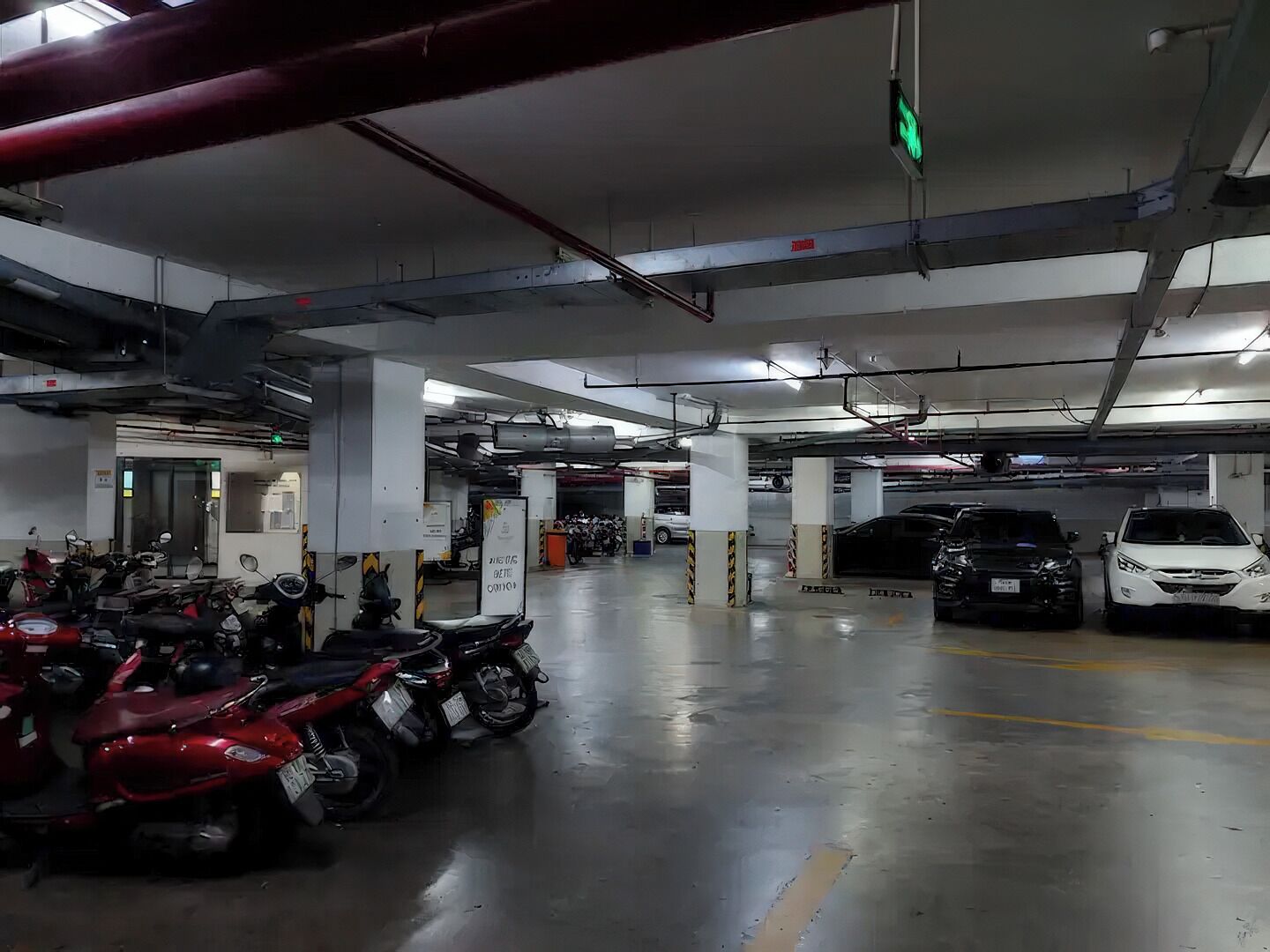 Un estacionamiento de varios niveles con varias motocicletas y automóviles aparcados.