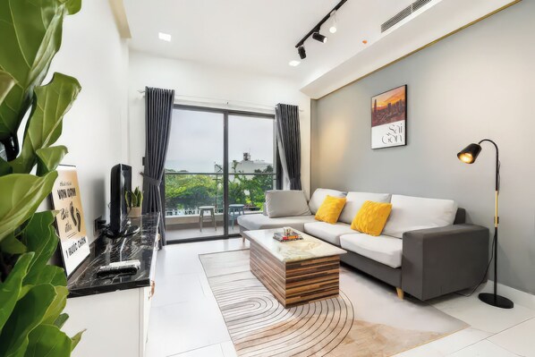 A modern living room with a sofa, a coffee table, and a large window.