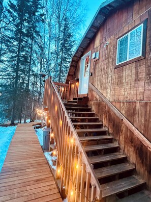 A wooden cabin with a wooden staircase leading to a deck.