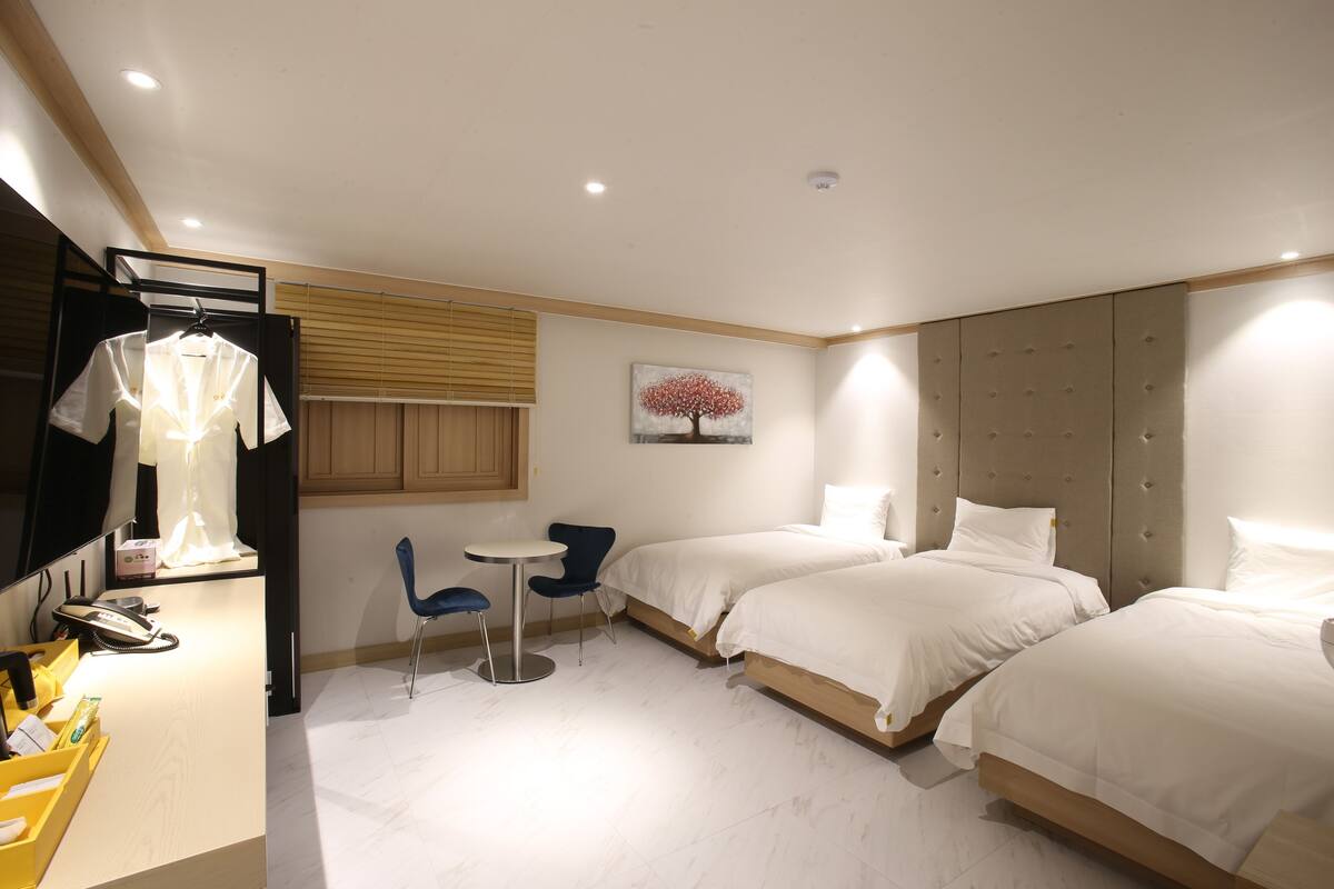 Ein Hotelzimmer mit zwei Betten, einem Schreibtisch, einem Telefon, einem Stuhl und einem kleinen Tisch.