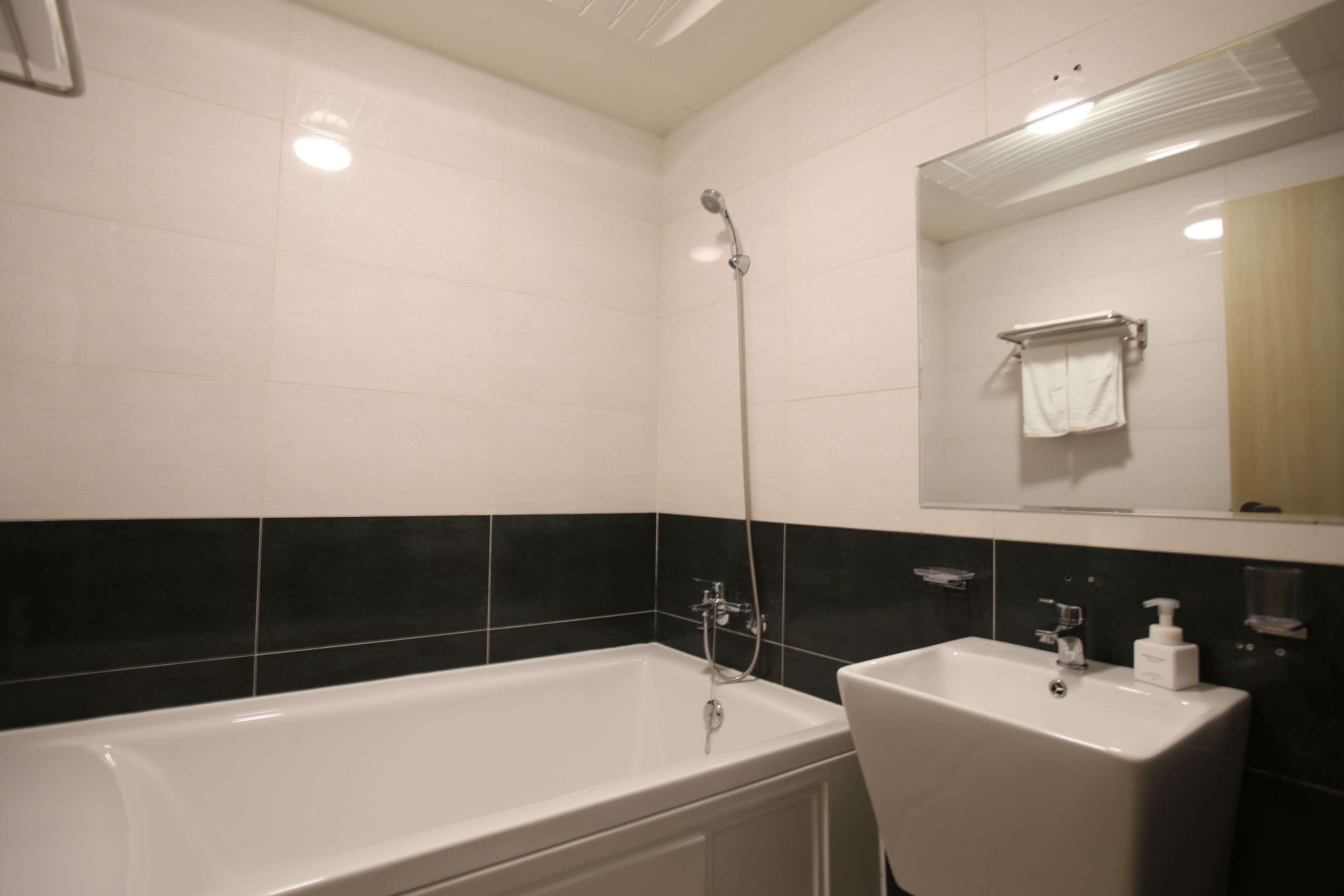 A bathroom with a bathtub, a sink, and a mirror.