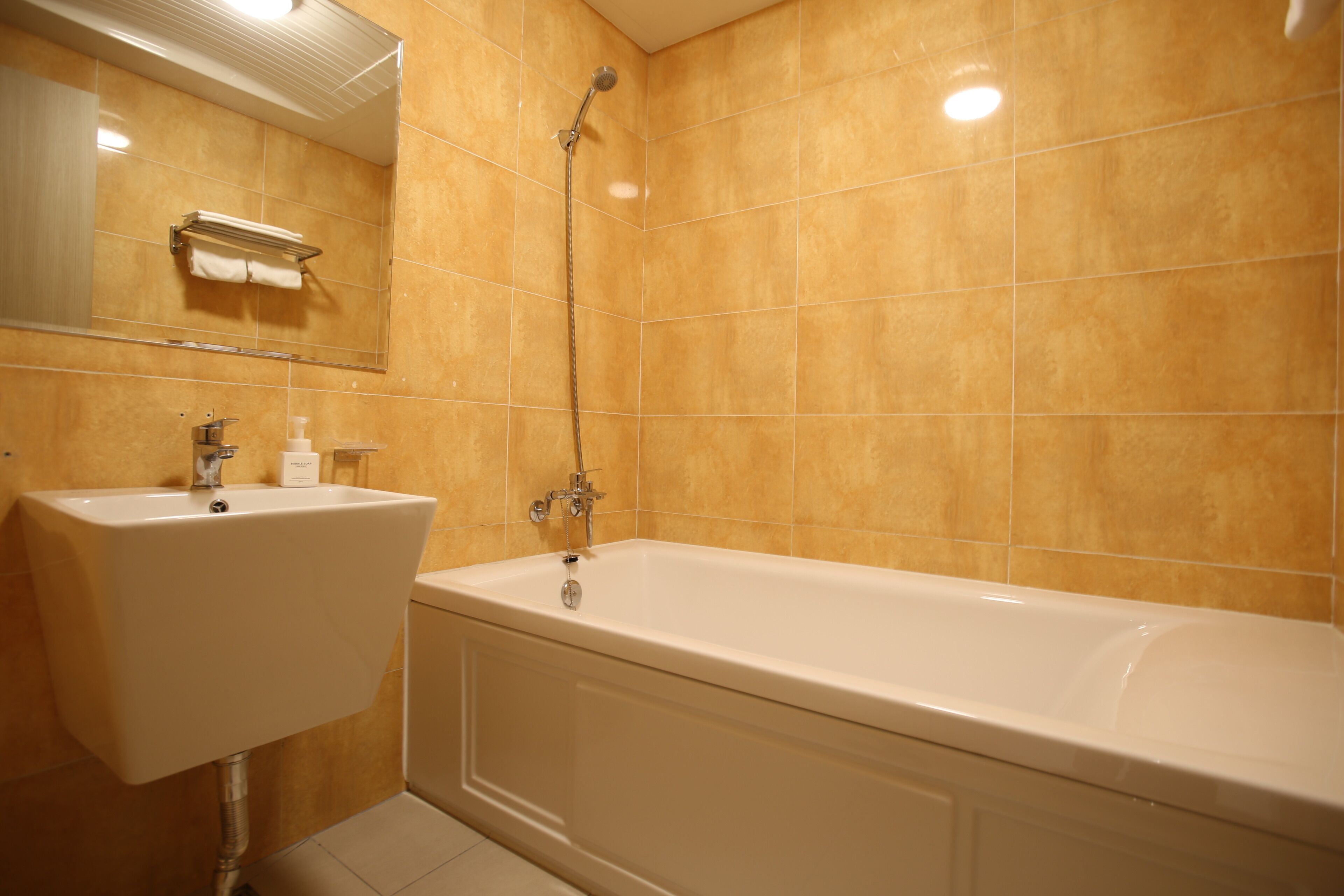 A bathroom with a sink, mirror, and bathtub.