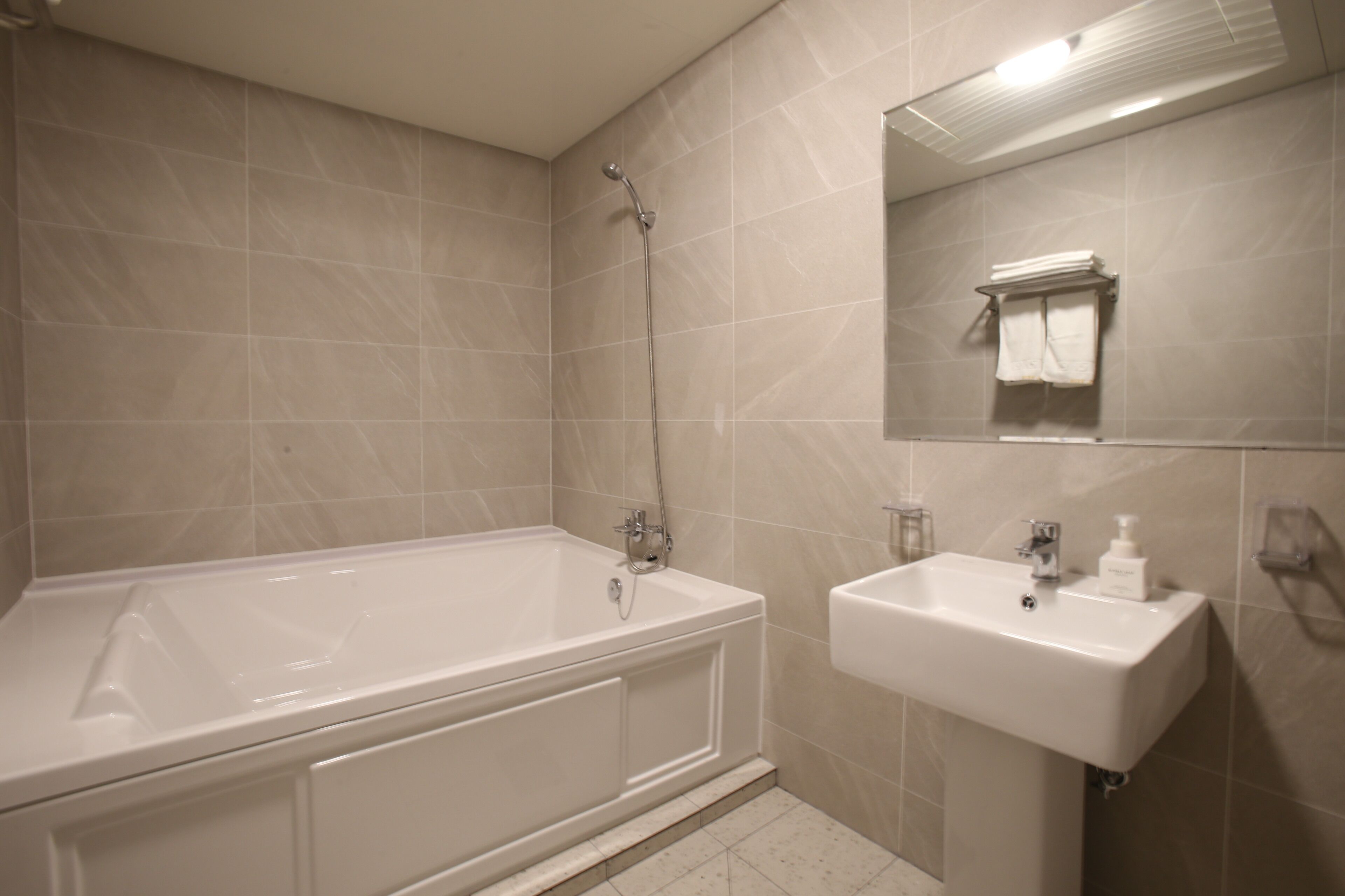 A bathroom with a bathtub, a sink, and a mirror.