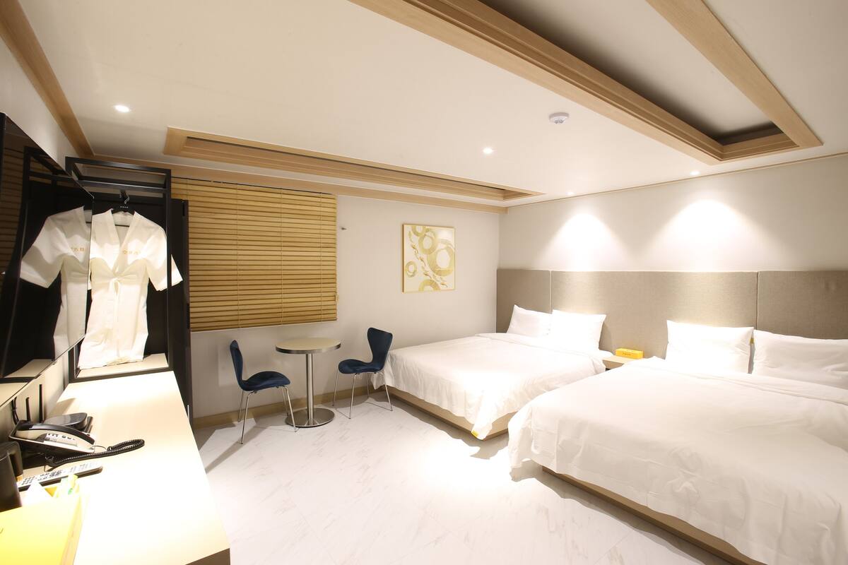 Ein Hotelzimmer mit zwei Betten, einem Schreibtisch mit Telefon und einem Sessel.