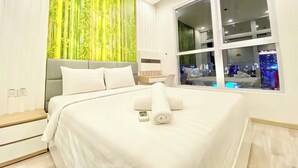 Une chambre d’hôtel moderne avec un grand lit, une vue sur la ville par la fenêtre et un mur décoré sur le thème du bambou.