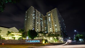 Un grand hôtel, avec un panneau lumineux indiquant «THE GARDEN» la nuit.