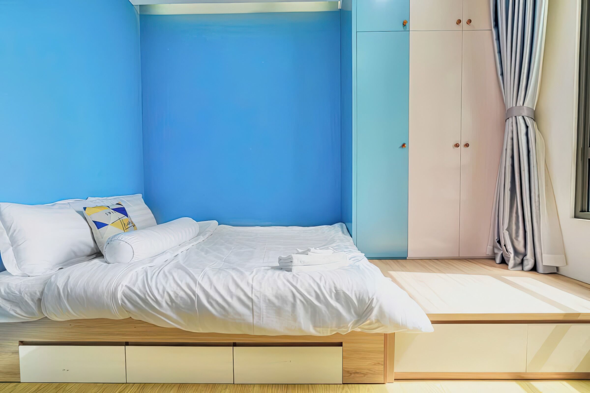 Quarto moderno com cama, espaço de armazenamento embutido e vista para o exterior.