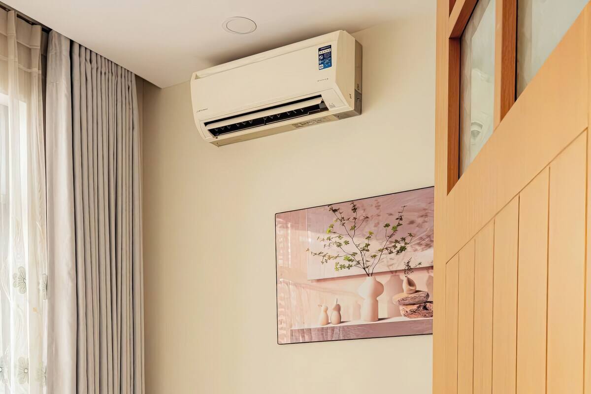Une chambre à coucher avec un lit, une armoire en bois, un climatiseur fixé au mur et un tableau au-dessus du lit.