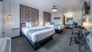 A hotel room with two beds, a desk, a chair, a small kitchenette, and a ceiling fan. - 3-Hansen Inn & Cabins, Room, Double Queen, Ground Floor, No Smoking, No Pets (Wall)
