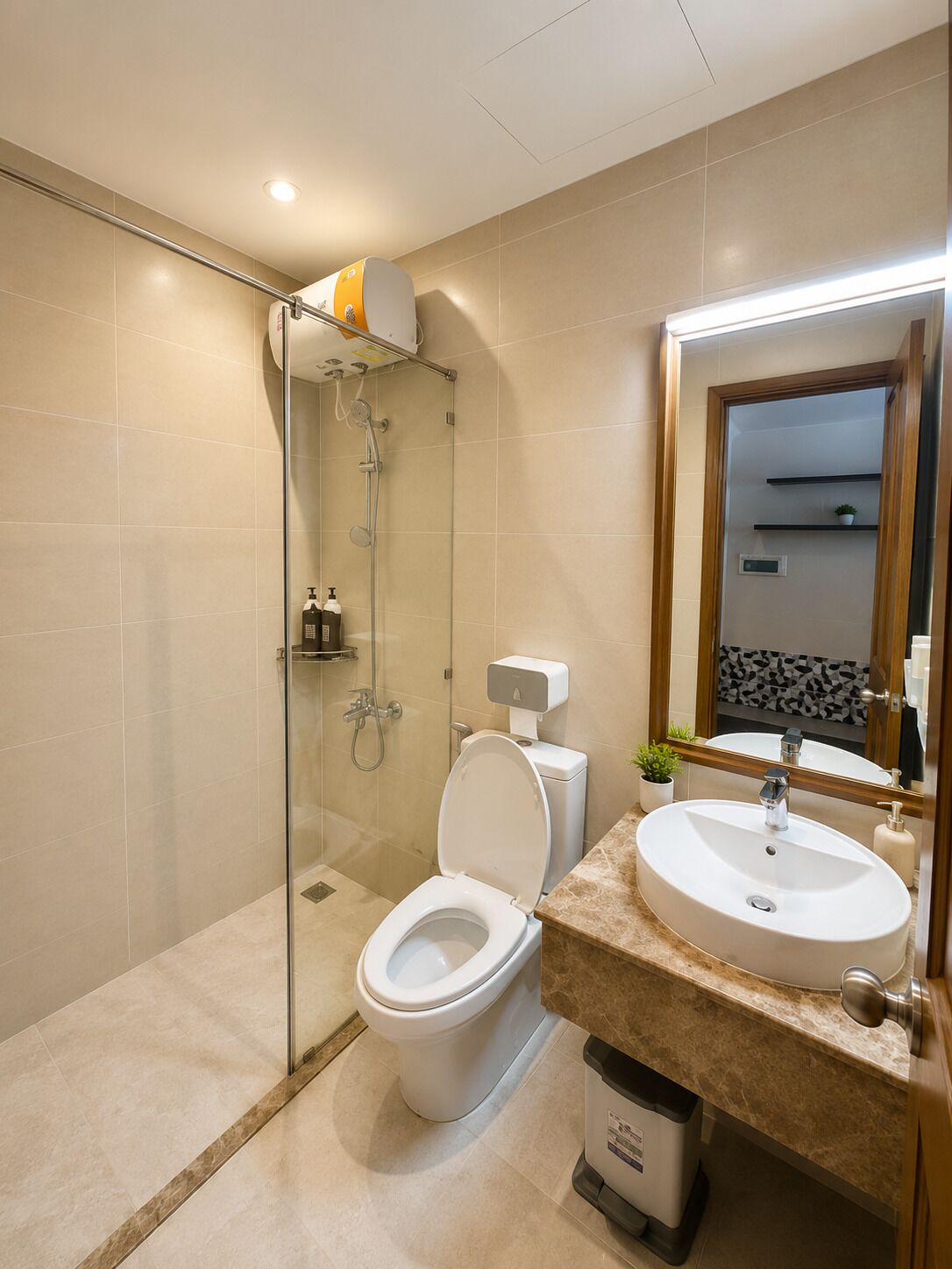 Ein modernes Badezimmer mit einer gläsernen Duschkabine, einer Toilette und einem Waschbecken mit Spiegel.