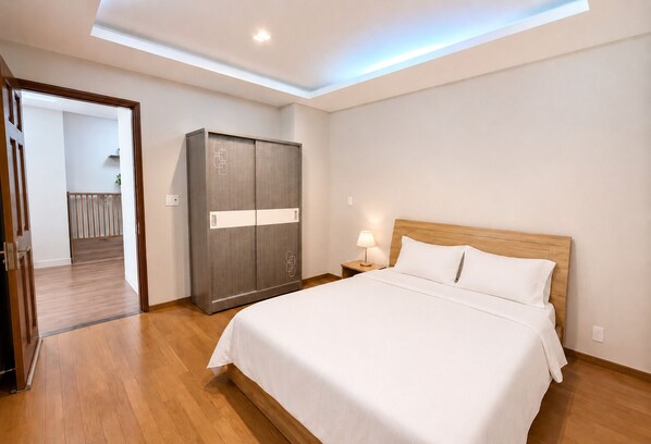 Une chambre d’hôtel avec un lit, une armoire, une table de chevet et un luminaire au plafond.