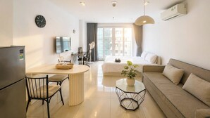 A modern living room with a sofa, a dining area with a table and chairs, a TV, and a large window with curtains. - RAINBOW Sky Center TSN Airport (Ho Chi Minh City)