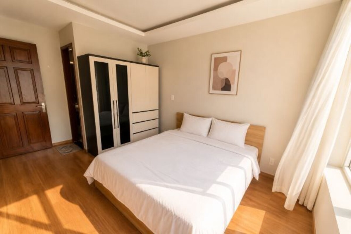 A bedroom with a bed, wardrobe, and a painting on the wall.