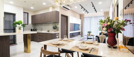 A modern kitchen with a dining area, featuring a chandelier, wooden cabinets, and a dining table set for four.