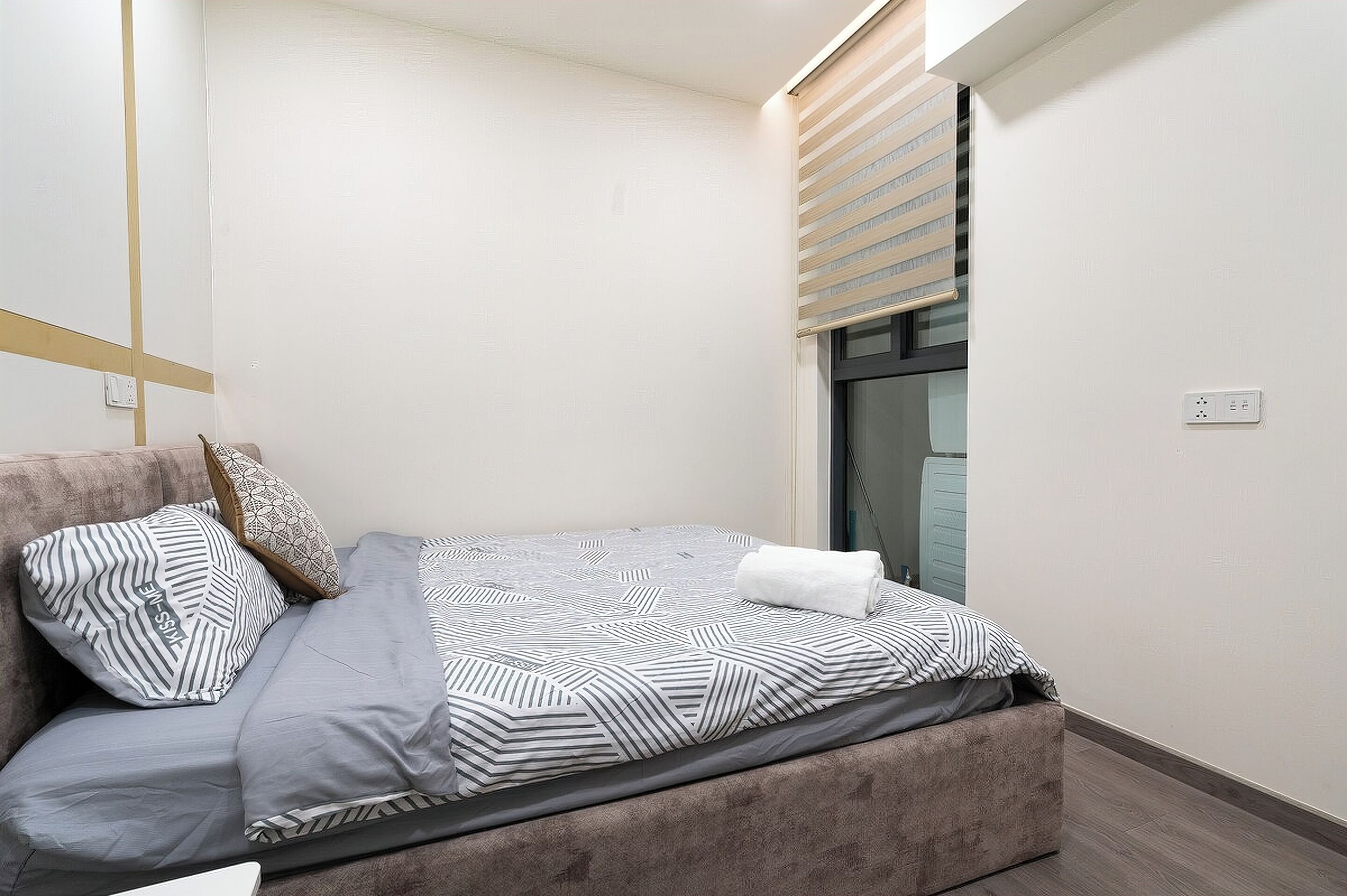 A neatly made bed with striped bedding, a pillow, and a folded towel.