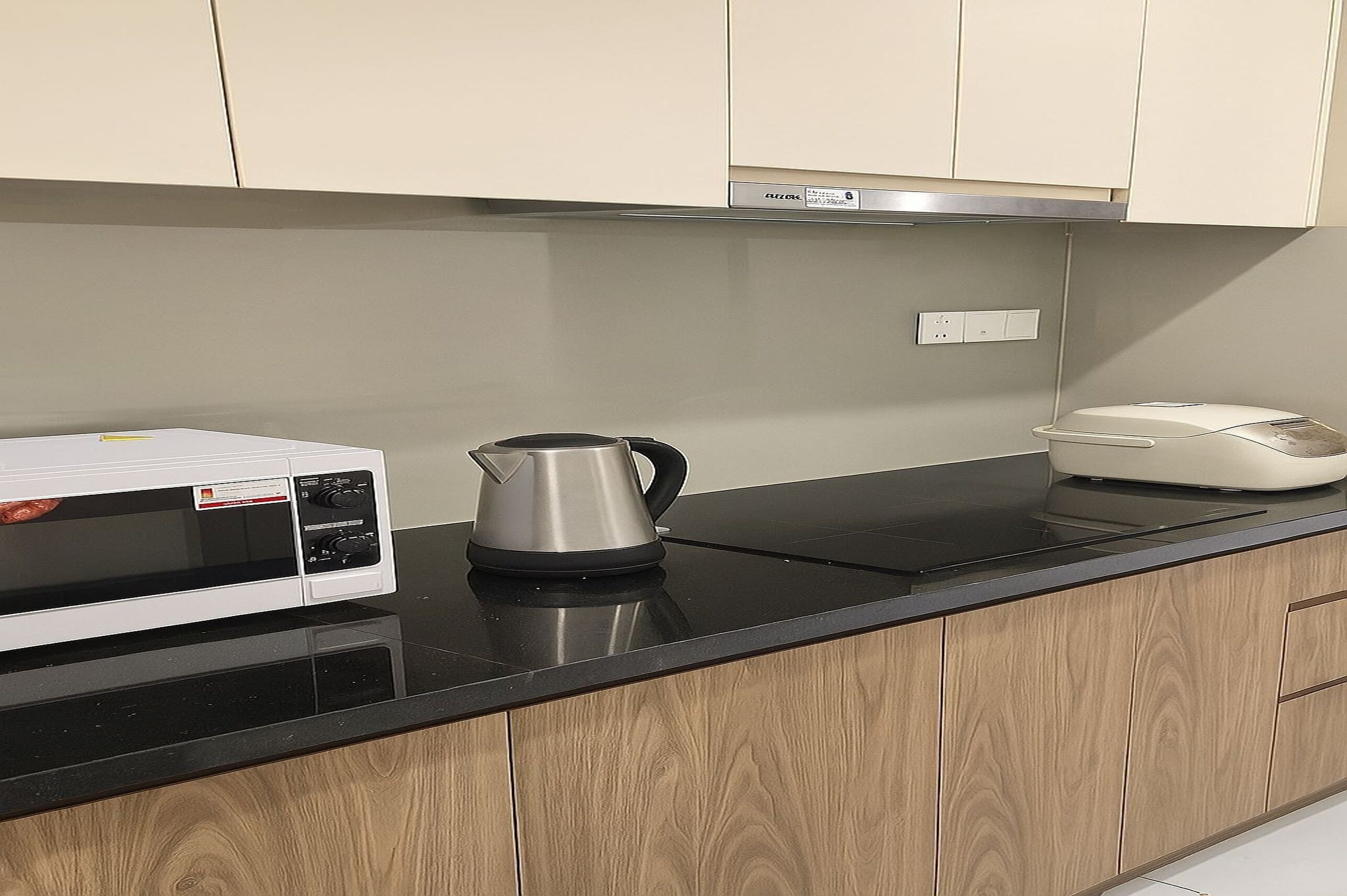 A kitchen with a microwave, kettle, and a coffee maker on the counter.