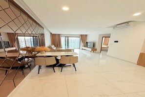 A modern living room with a dining area, a TV, and a large window with curtains. - Urban Zen Saigon - Celadon Aeon Mall (Ho Chi Minh City)