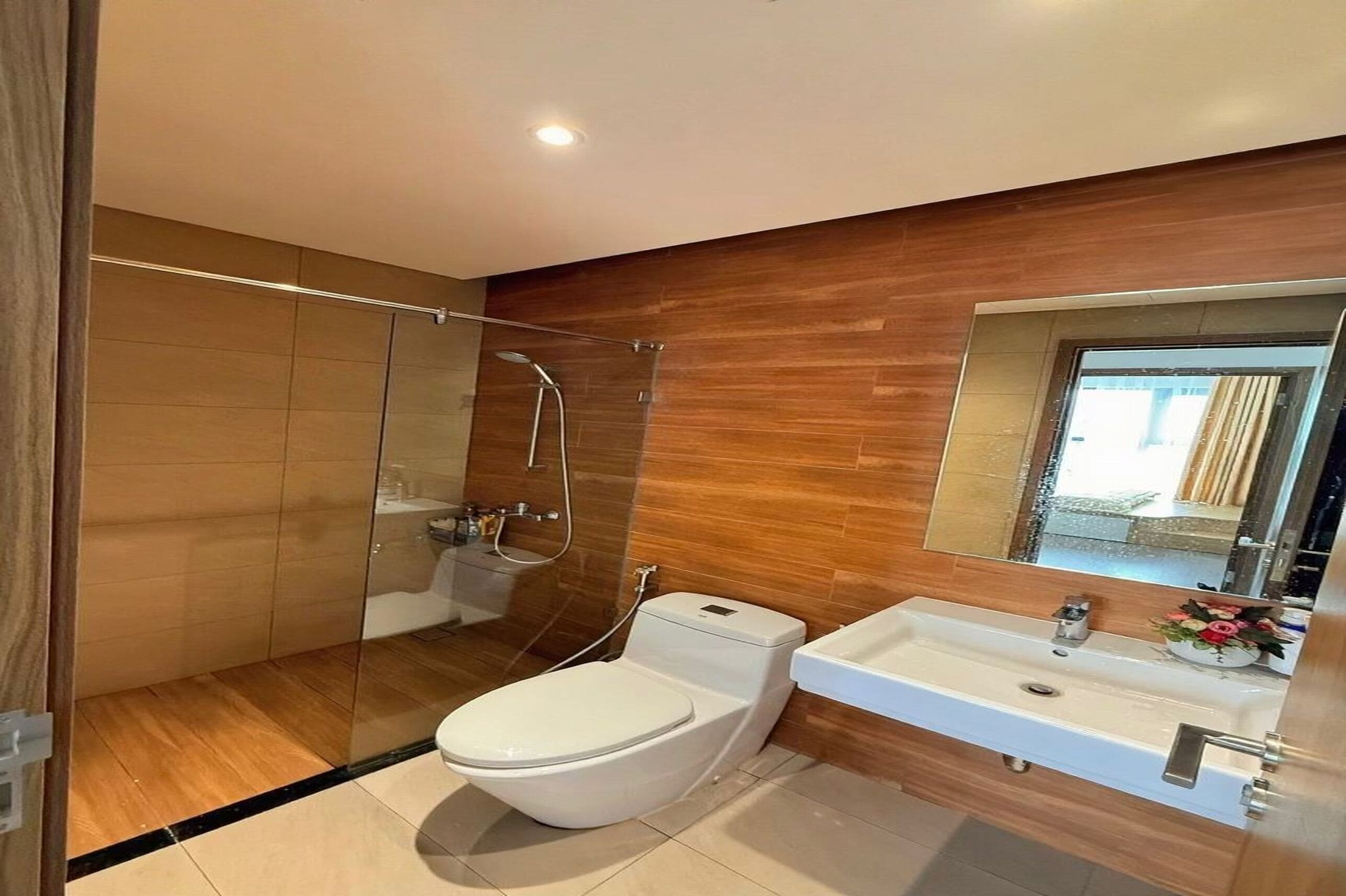 A modern bathroom with a glass shower enclosure, a white toilet, and a sink with a mirror above it.
