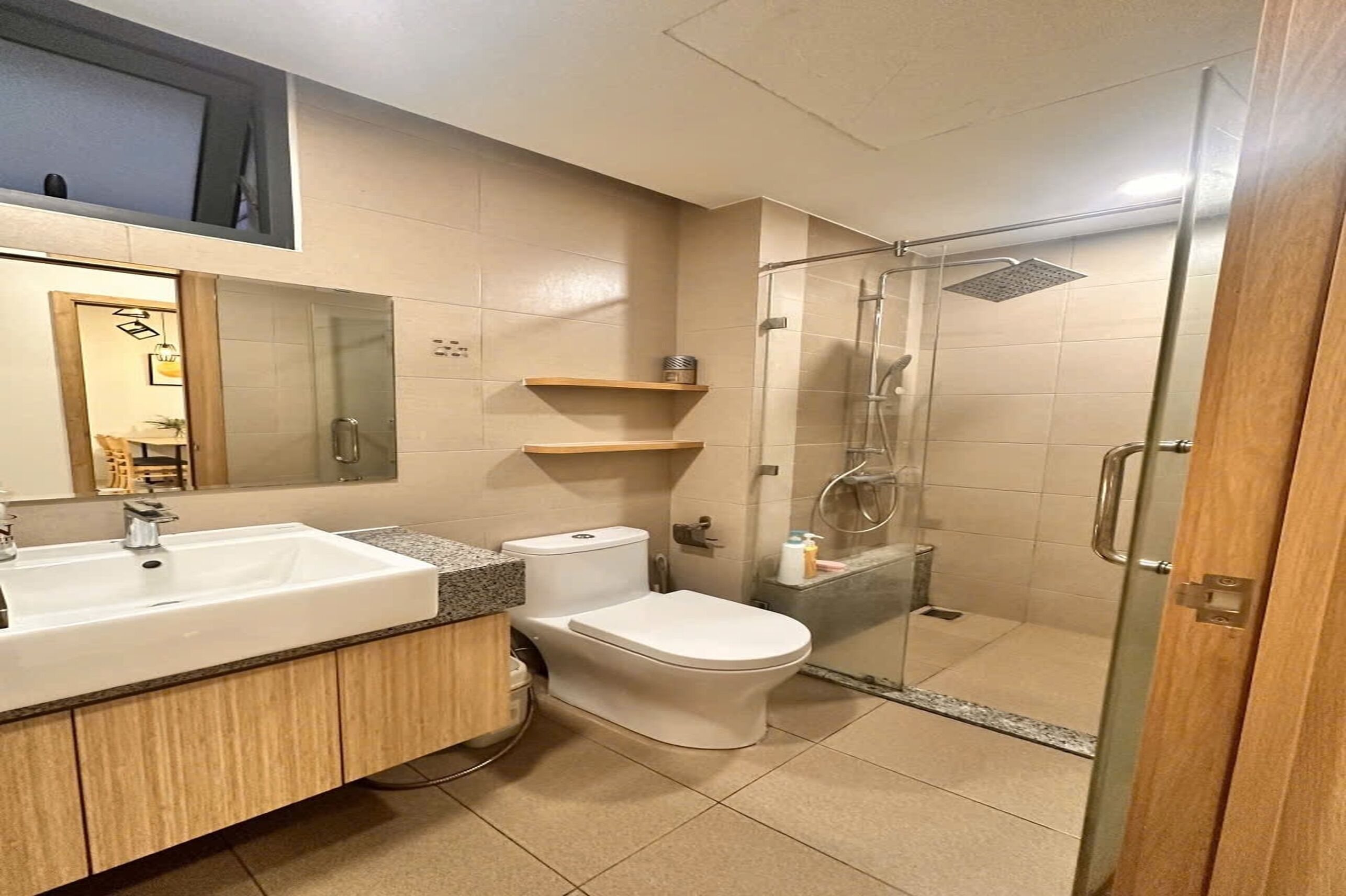 Un baño con lavamanos, inodoro y ducha con mampara de vidrio.