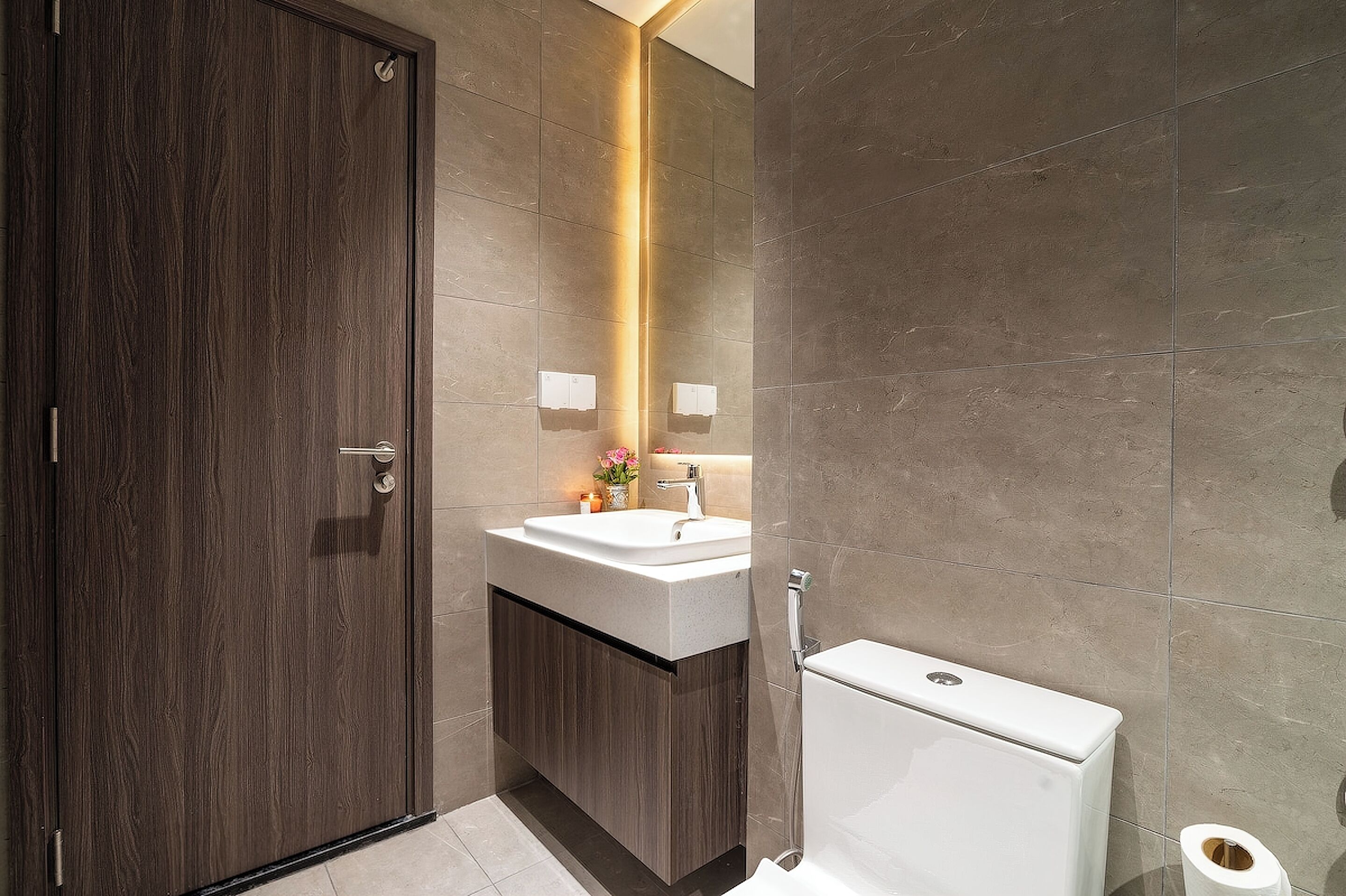 A bathroom with a wooden door, a white sink, a mirror, and a toilet.