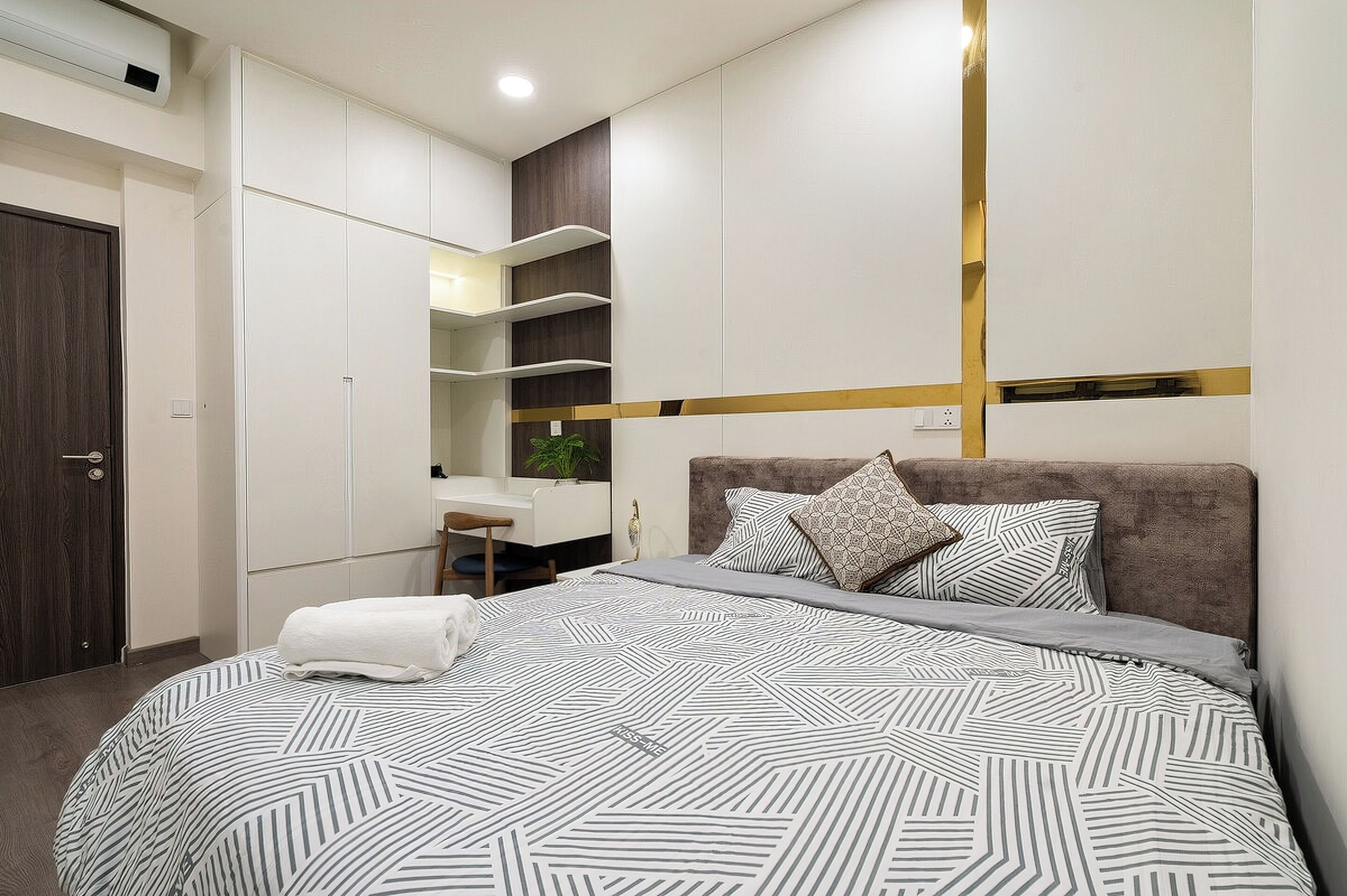 A bedroom with a bed, a desk, and built-in shelving.