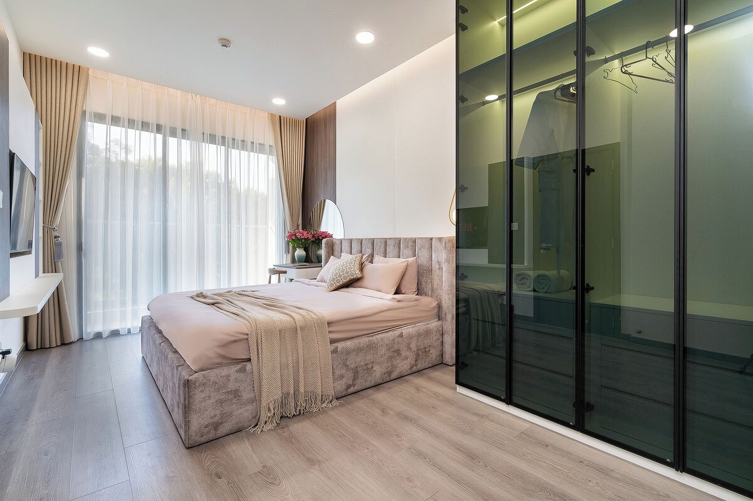 Ein modernes Schlafzimmer mit einem großen Bett, einer Glasdusche und einem Flachbildfernseher.
