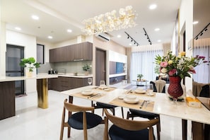 Una cocina moderna con comedor, que incluye una araña, armarios de madera y una mesa de comedor preparada para cuatro personas.