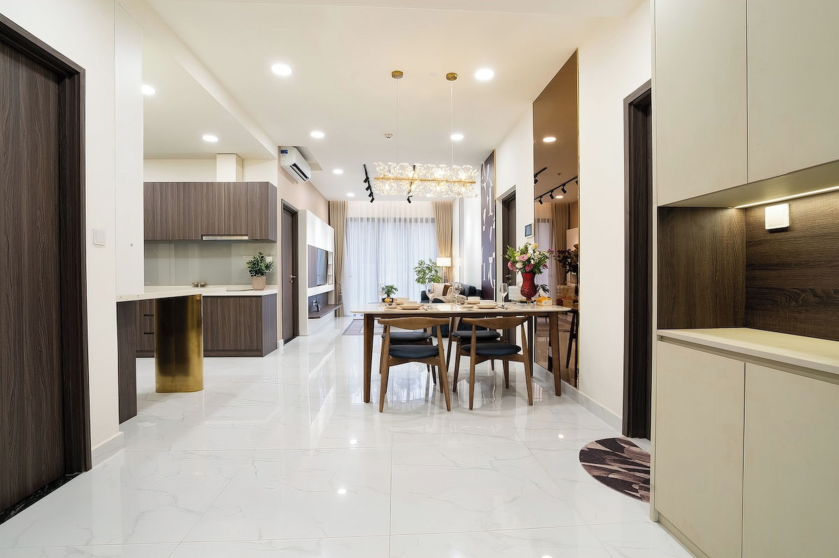 A modern kitchen with a dining area, featuring a central island, pendant lighting, and a view into the living area.
