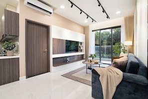 A modern living room with a flat-screen TV, dark sofa, and a dining area with a round table. - GEM EMERALD - Celadon City Tan Phu (Ho Chi Minh City)
