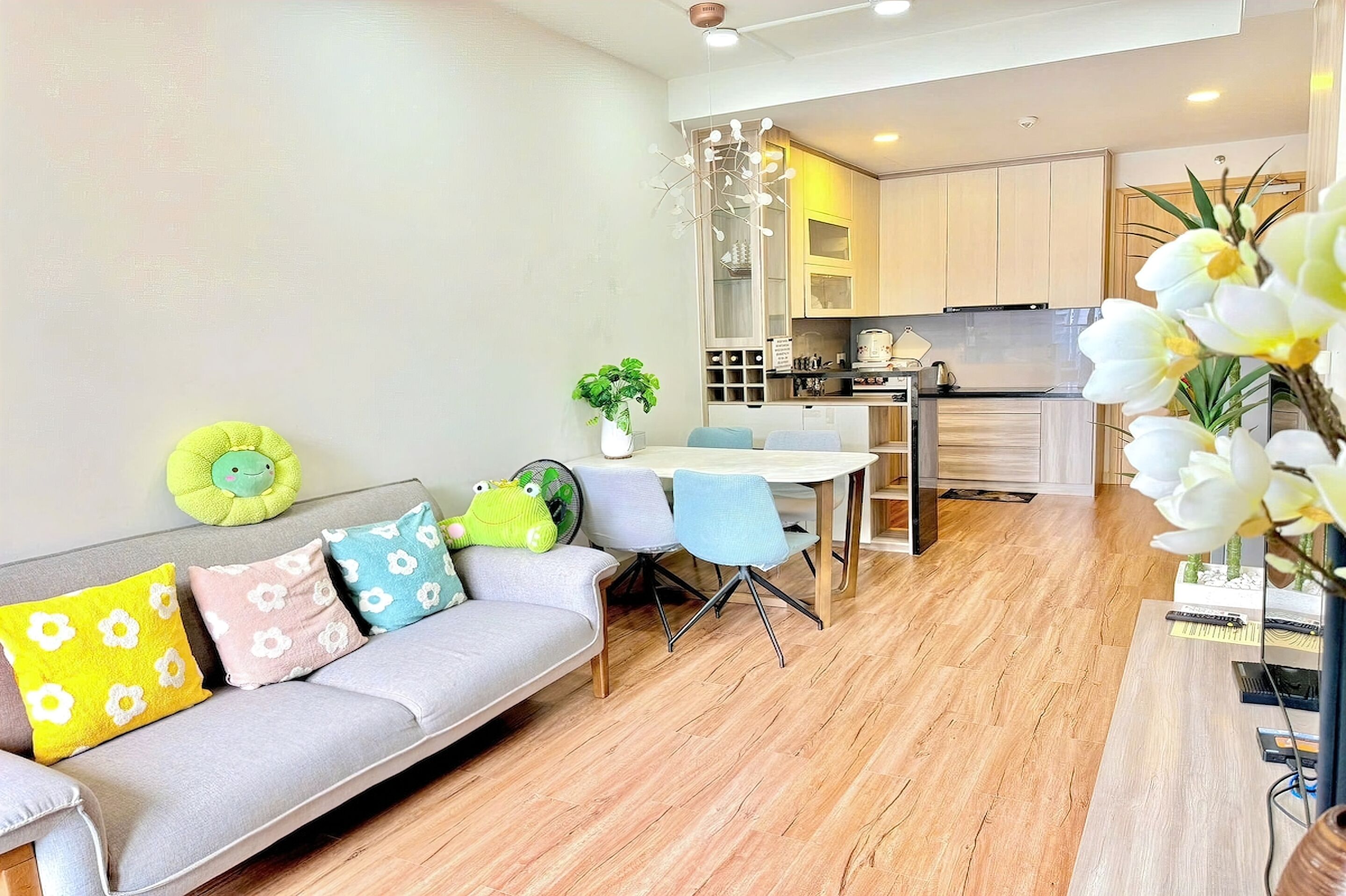 A modern living room with a sofa, chairs, a dining table, and a kitchen in the background.