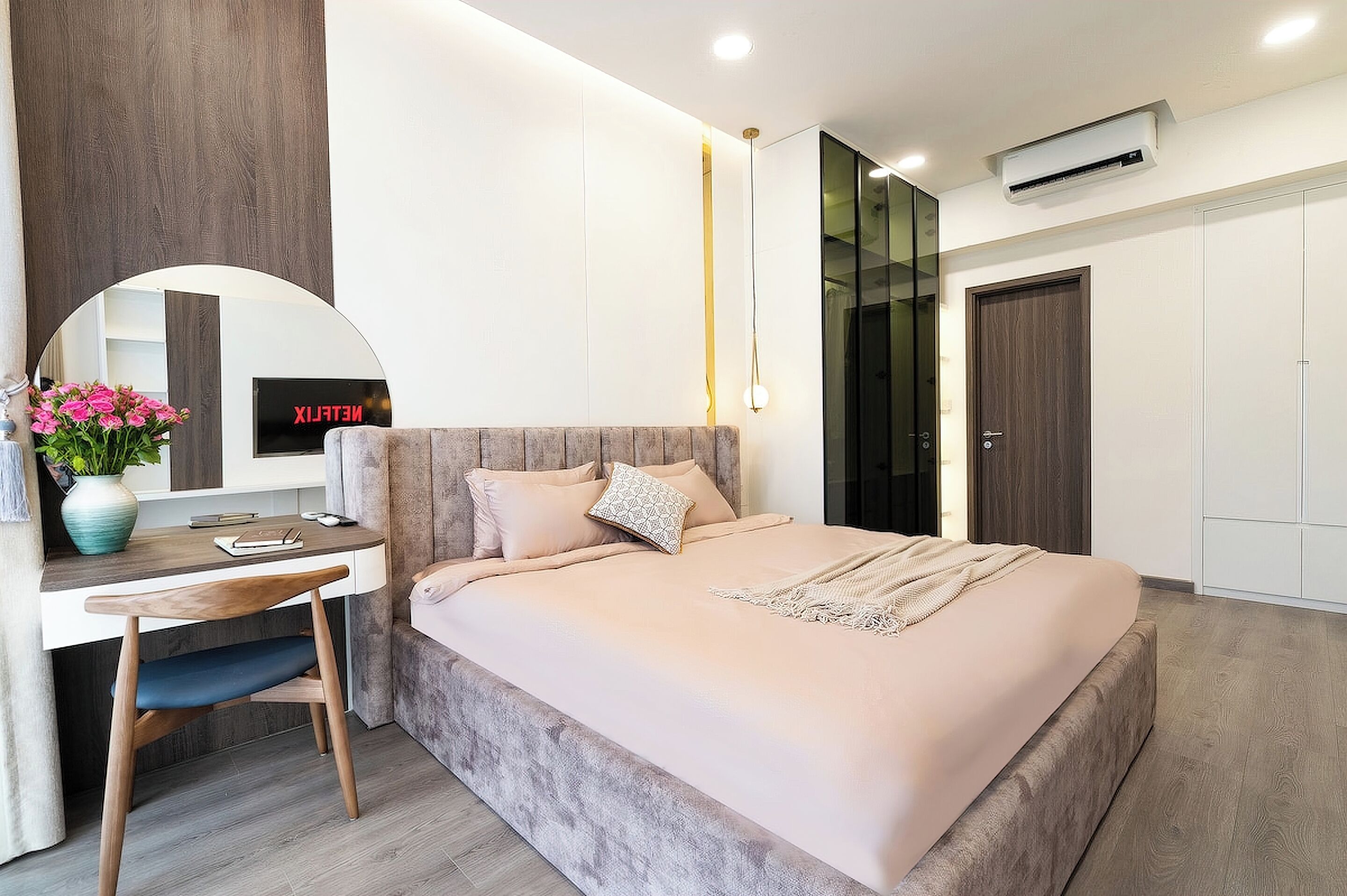Un dormitorio moderno con cama, escritorio, silla y un espejo grande.