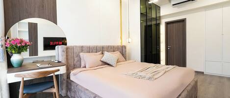 Un dormitorio moderno con cama, escritorio, silla y un espejo grande.