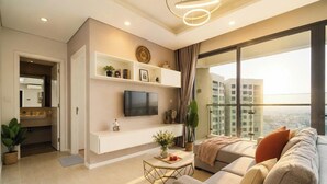 A modern living room with a flat-screen TV, a sofa, a coffee table, and a balcony with a city view. - Diamond Island - Mekong Retreat Apartment (Ho Chi Minh City)