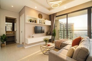 Una sala de estar moderna con una televisión de pantalla plana, un sofá, una mesa de centro y un balcón con vista a la ciudad.