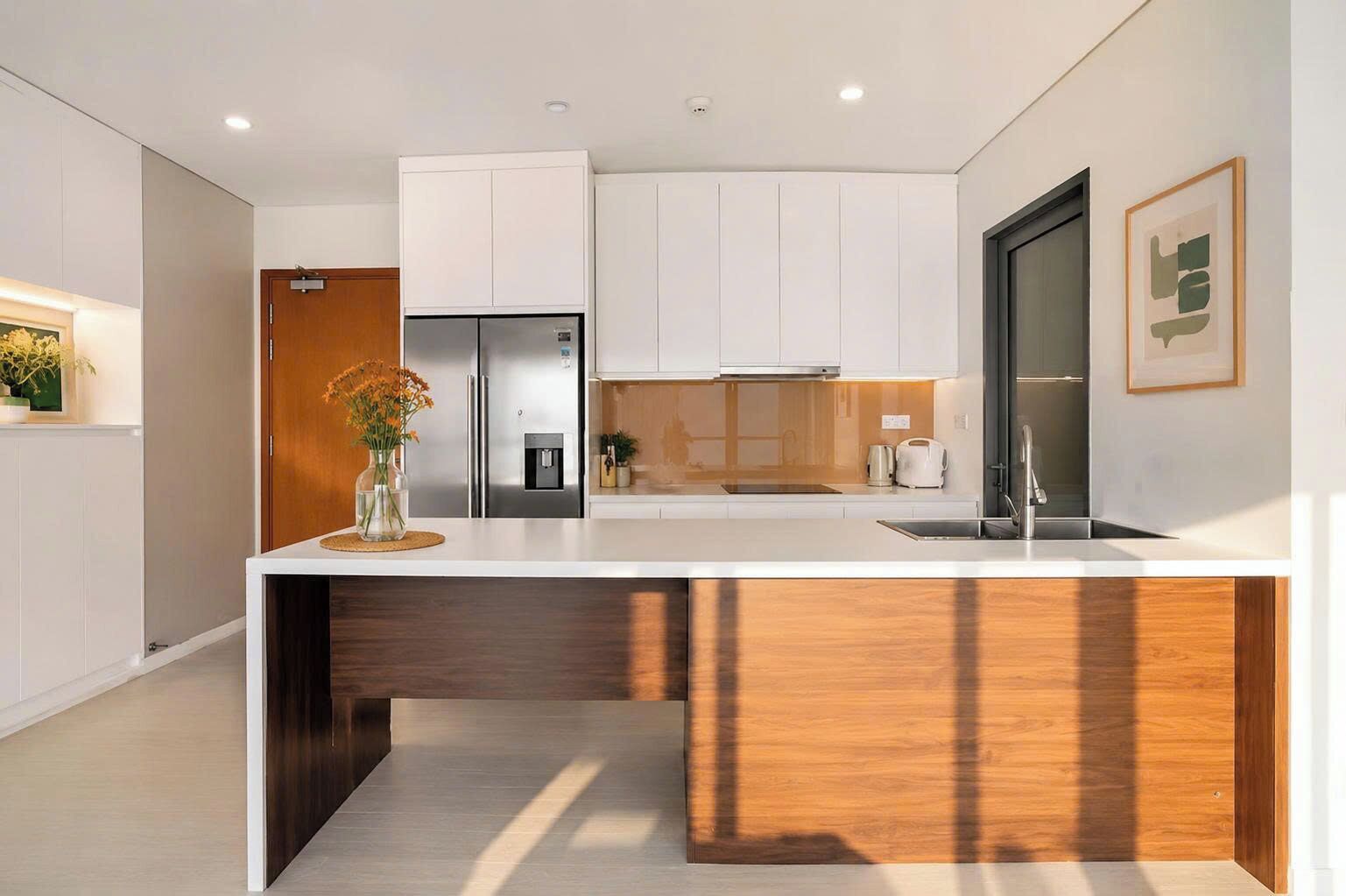 A modern kitchen with white cabinetry, a stainless steel refrigerator, a built-in oven, and a wooden accent on the island.