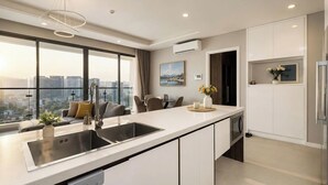 A modern kitchen with a large island, a dining area, and a view of the city. - Diamond Island - Mekong Retreat Apartment (Ho Chi Minh City)