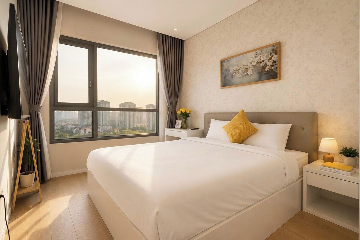 A hotel room with a large bed, a nightstand, a bedside table, a TV, and a window with curtains.