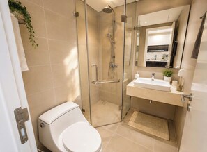 Un bagno moderno con box doccia in vetro, un water bianco, un lavandino con specchio sopra e una piccola pianta in vaso.
