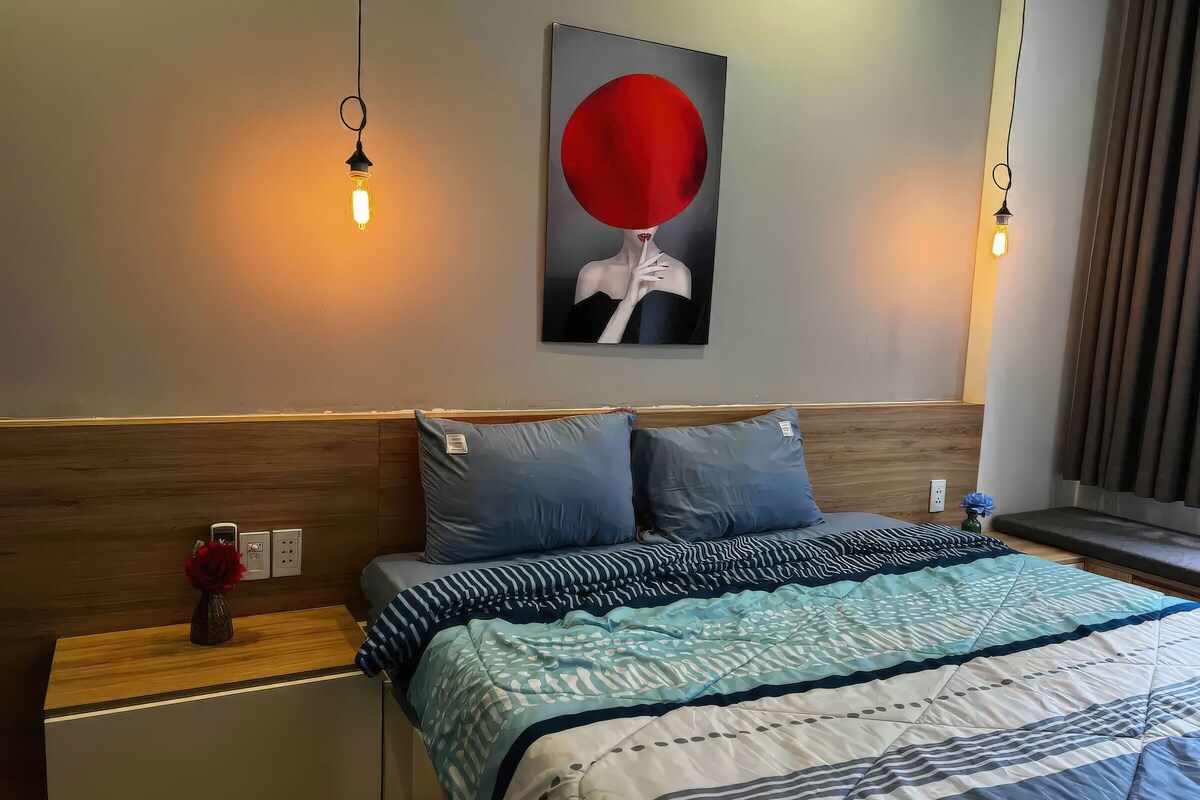 Ett välordnat hotellrum med en säng, två sängbord, ett konstverk som hänger på väggen och ett fönster med gardiner.