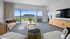 A modern living room with a large TV, a sofa, a coffee table, and a view of the sea. - Rose's Villa (Stanley)