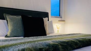 A neatly made bed with a dark headboard, white pillows, and a green throw blanket.