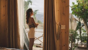 A person standing at a wooden door with curtains, looking outside. - Windy Hill Homestay (Xuan Truong - Da Lat)
