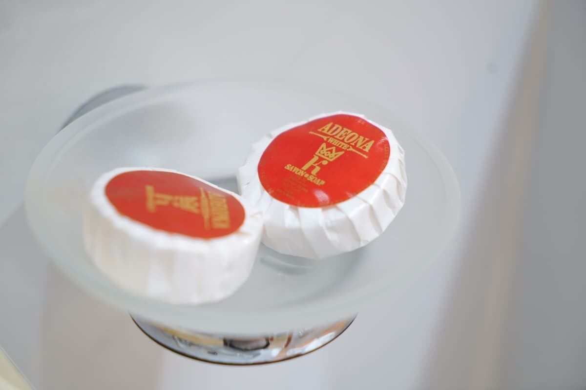 Two white soap bars with red labels in a clear glass container.
