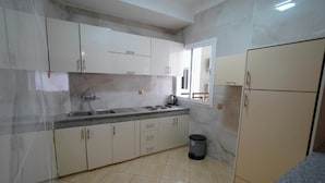 A kitchen with white cabinets, a sink, and a window. - Apartments next to the beach  (Agadir)