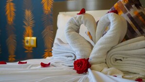 A neatly made bed with towels arranged in a heart shape, a red rose, and a patterned wall in the background. - Apartments next to the beach  (Agadir)