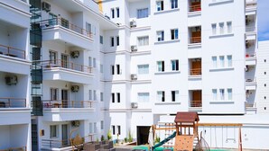 A multi-story hotel with a swimming pool, outdoor seating, and a children's play area. - Apartments next to the beach  (Agadir)