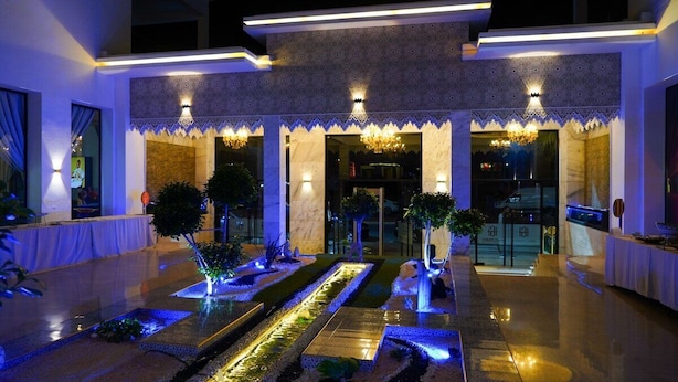 A modern hotel entrance with a water feature, decorative lighting, and a patterned facade. - Apartments next to the beach  (Agadir)